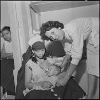 Portrait d'une femme et de son enfant assis, assistés par une monitrice, à l'intérieur d'une antenne médicale.