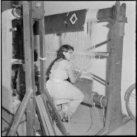 Portrait d'une jeune femme qui confectionne un tapis.