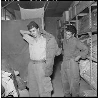 Portrait d'un jeune harki qui enfile sa tenue à l'intérieur du magasin d'habillement de Palestro.