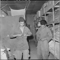 Portrait d'un jeune harki qui enfile sa tenue à l'intérieur du magasin d'habillement de Palestro.