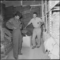 Portrait d'un harki qui enfile sa tenue à l'intérieur du magasin d'habillement de Palestro.