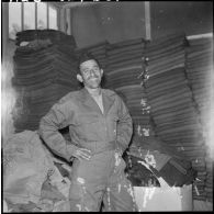 Portrait d'un harki qui pose dans sa nouvelle tenue à l'intérieur du magasin d'habillement de Palestro.