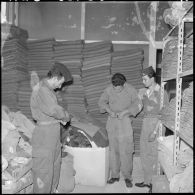 Portrait de harkis qui enfilent leurs tenues à l'intérieur du magasin d'habillement de Palestro.