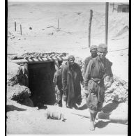 Photographie : un jeune garçon précède un groupe d'hommes à la sortie d'un abri souterrain.