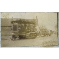 [Un tracteur chenillé Holt Caterpillar remorque plusieurs pièces d'artillerie dans la rue d'un village].