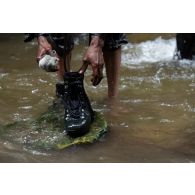 Un soldat congolais retire sa chaussure pour une progression en milieu aquatique en forêt à Libreville, au Gabon.