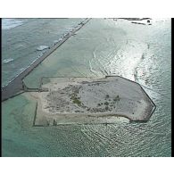 Vues aériennes de l'atoll de Moruroa (Mururoa) et des installations du Centre d'expérimentation du Pacifique (CEP), et aperçu de la flore sur la rive du lagon.