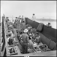 Prisonniers de guerre de l'Union française libérés par l'Armée populaire vietnamienne installés dans la cuve d'un chaland de débarquement au cours de leur rapatriement vers Hanoï.