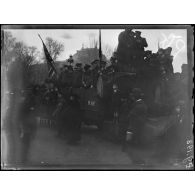 Paris. Visite du roi et de la reine des Belges. Spectateurs perchés sur un camion avenue des Champs-Elysées. [légende d'origine]