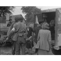 Normandie 1944 (actualités américaines) - A La Colombe, des civils français blessés par un schrapnel sont pris en charge et soignés par des infirmiers américains.