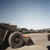 Parc d'engins du génie et de camions à benne dans un camp militaire, peut-être à Arue.