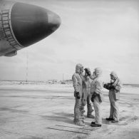 Au pied d'un avion Vautour, deux membres de l'équipe de décontamination mesurent à l'aide d'un détecteur la radioactivité sur les pilotes en tenue de protection, sur l'atoll d'Hao.