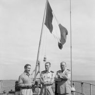 Photographie de groupe de Jean Viard, directeur des essais, avec le général de corps aérien Jean Thiry, directeur des centres d'expérimentations nucléaires (DIRCEN), et le vice-amiral Jean Lorain, commandement du groupe opérationnel des expérimentations nucléaires (GOEN), à bord probablement du croiseur De Grasse.