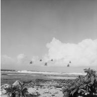 Vol en formation de six hélicoptères Alouette II, probablement du groupe aérien mixte 82 (GAM 82), en basse altitude au-dessus du rivage à Moruroa.