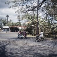 Femmes tahitiennes circulant en solex et à scooter dans une rue de Papeete (cours de l'Union sacrée), à proximité d'une station service.