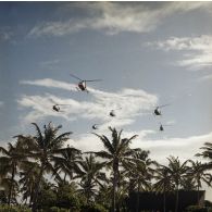 Vol en formation à basse altitude de six hélicoptères Alouette II, probablement du groupe aérien mixte 82 (GAM 82), à Moruroa.