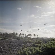 Vol en formation de six hélicoptères Alouette II, probablement du groupe aérien mixte 82 (GAM 82), près de l'aéroport à Moruroa.