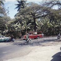 Automobiles et deux-roues circulant dans une rue de Papeete.