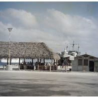 L'escale au port de l'atoll de Moruroa. En arrière-plan le bâtiment base (BB) Maurienne (A637) et un transport de chalands de débarquement (TCD) à quai.