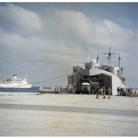 L'escale au port de l'atoll de Moruroa. En arrière-plan le bâtiment base (BB) Maurienne (A637) et débarquement du transport de chalands de débarquement (TCD) portière ouverte à quai.