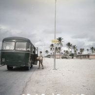 Locaux récents de la zone de vie de la base avancée d'Hao. Un militaire monte dans un autobus devant le panneau "Parmentier".