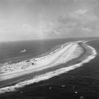 Vue aérienne de la piste d'atterrissage de l'atoll de Moruroa. Un transport de chalands de débarquement (TCD) (Ouragan ?) dans le lagon.