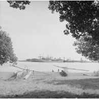 Le port de Papeete et des pirogues à balancier au premier plan. Le pétrolier-ravitailleur Isère (A675) à quai.