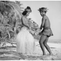 Un couple de danseurs, coiffés d'une couronne fleurie, fait une démonstration de danse du Tamoure sur une plage de l'atoll d'Hao.