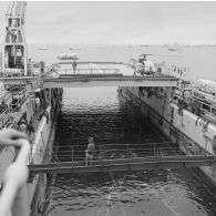 Deux barges transportant des shelters se dirigent vers l'entrée du radier du transport de chalands de débarquement (TCD) Ouragan dans le lagon de l'atoll de Moruroa.