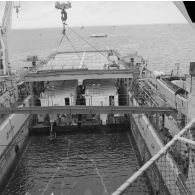 Deux barges transportant des shelters entrent dans le radier du transport de chalands de débarquement (TCD) Ouragan sous le regard de l'équipage dans le lagon de l'atoll de Moruroa.