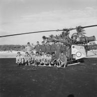 Photographie de groupe d'équipages d’hélicoptère Alouette II peut-être du groupe aérien mixte 82 (GAM 82) sur la zone de poser à Moruroa.