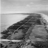 Vue aérienne de l'atoll de Moruroa. Au loin le site du poste de commande de tir (PCT) Anémone.