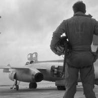 Pilote portant son casque sous le bras au pied d'un avion Vautour sur la base de Hao.