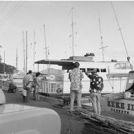 Ambiance sur un quai du port de plaisance de Papeete : au débarcadère, panneaux d'informations et de tarifs pour des promenades en mer vers l'île de Moorea.