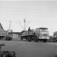 Sur un quai du port de Papeete au pied d'un cargo, un ouvrier vérifie un chargement de caisses sur la remorque d'un camion.