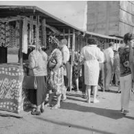 Au port de Papeete, des touristes achètent des colliers de coquillage exposés sur des étals.