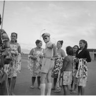 Sur un parking de l'aéroport de Faa'a à Papeete, un lieutenant achète des colliers de coquillage à des femmes tahitiennes .