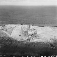 Vue aérienne du poste d'enregistrement avancé (PEA) Dindon [ou Denise ?] sur l'atoll de Moruroa et de barges dans le lagon.