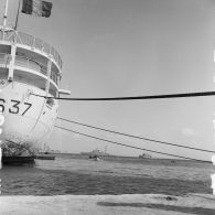 En arrière-plan du bâtiment-base (BB) Maurienne (A637) à quai au port de Moruroa, la force Alpha au mouillage dans le lagon, dont le croiseur De Grasse (C610) et le remorqueur de haute-mer Hippopotame (A660).