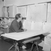 Le bureau météo à bord du croiseur de commandement De Grasse. Portrait d'un technicien dessinant sur une carte installée à une table à dessin. Au mur une date sur une carte indique 27 juin 1966.