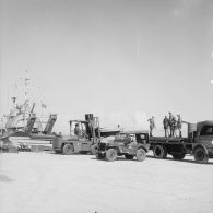 Sur un quai du port de Moruroa, des légionnaires chargent du matériel à l'aide d'un engin de levage à bord d'un camion près de la gabare Scorpion (A728).