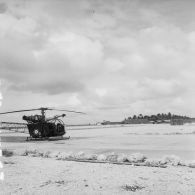 Hélicoptère Alouette II sur la zone de poser de l'atoll d'Hao. En arrière-plan, une zone technique.