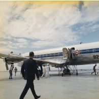 Le général Charles De Gaulle, président de la République, suivi de son aide de camp, descend par la passerelle de l'avion à l'aéroport de Moruroa, accueilli par Jean Viard, directeur des essais, et le vice-amiral d’escadre Jean Lorain, commandant du groupe opérationnel des expérimentations nucléaires (GOEN).