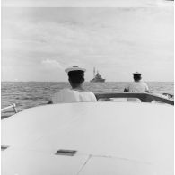 Marins à bord d'une vedette se dirigeant vers le croiseur De Grasse au mouillage dans le lagon de l'atoll de Morurua.