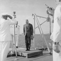 Pierre Messmer, ministre des Armées, rend les honneurs à son arrivée sur le croiseur de commandement De Grasse.