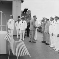 Le général Charles De Gaulle, président de la République, salue des officiers supérieurs aux côtés du capitaine de vaisseau Michel Teisserenc, commandant du croiseur De Grasse, et du vice-amiral Jean Lorain, commandant du groupe opérationnel des expérimentations nucléaires (GOEN).