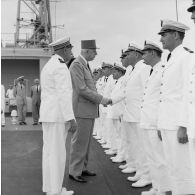 Le général Charles De Gaulle, président de la République, salue des officiers subalternes de marine aux côtés du capitaine de vaisseau Michel Teisserenc, commandant du croiseur De Grasse.