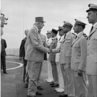 Le général Charles De Gaulle, président de la République, salue des officiers de l'armée de l'air aux côtés du général de brigade Maurice André, chef du service mixte de sécurité radiologique (SMSR), à bord du croiseur De Grasse.