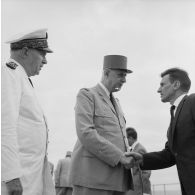 Le général Charles De Gaulle, président de la République, salue un personnel civil aux côtés du vice-amiral Jean Lorain, commandant du groupe opérationnel des expérimentations nucléaires (GOEN), à bord du croiseur De Grasse.