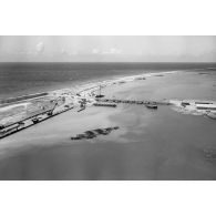 Vue aérienne du pont flottant de la Taunoa, en arrière-plan Motu uta, la digue et une partie du dock flottant de la marine, vers mai 1964.